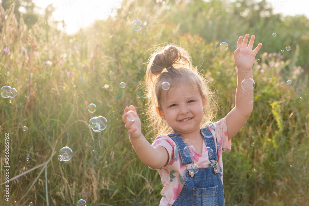 Little cute girl laughs playing with soap bubbles in nature Little cute girl laughs playing with soap bubbles in nature