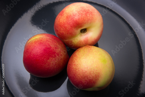 Apricots, peaches and nectarines on a black plate close-up photo