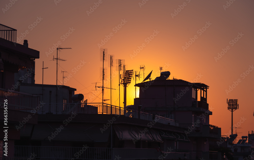 Sunset over city roofs with chimneys and antennas