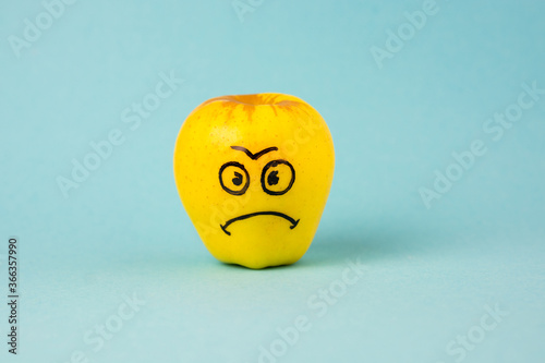 Fotografija apples face with negative emotion on it, yellow background