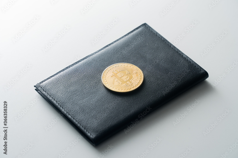 A man's black purse on a white insulated background. Bitcoin coin on top on purse