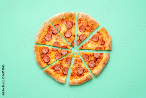 Pepperoni pizza flat lay on a green background. Sliced pizza isolated on a colored background