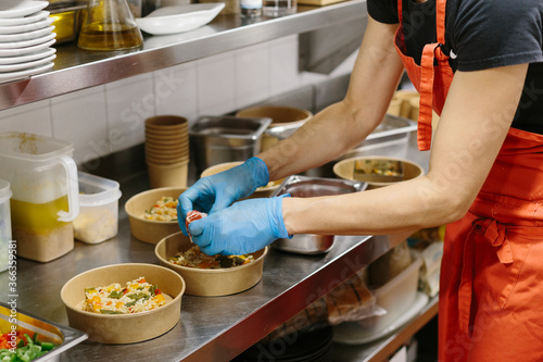 Cook preparing rice salads to take away. The containers used are compostable.