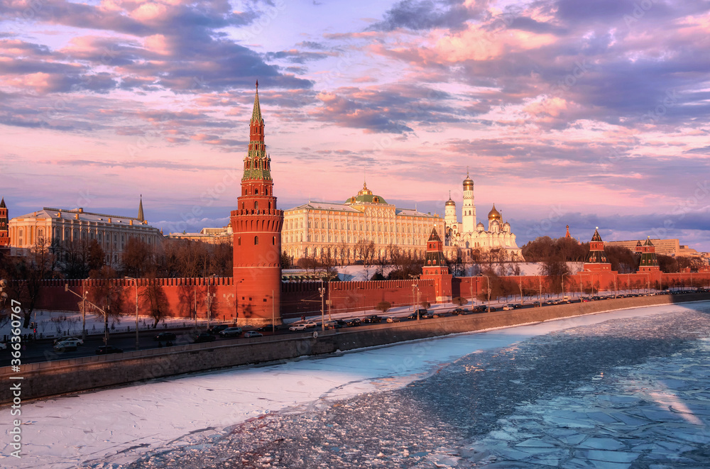 Red walls of sunset Kremlin in Moscow near iced river in winter