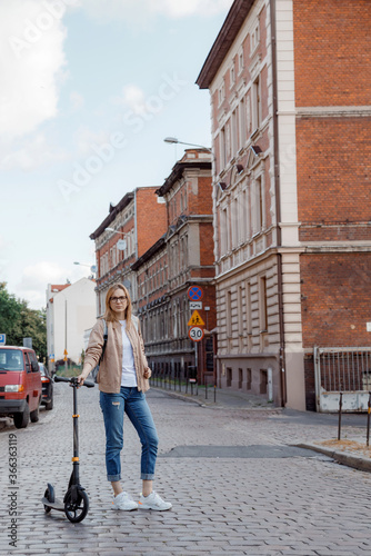 Young woman on a scooter in the city. Stylish girl rides a scooter. City trip.