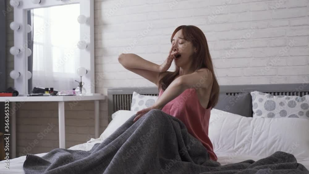 girl just waking up is stretching and yawning at home. woman in pink