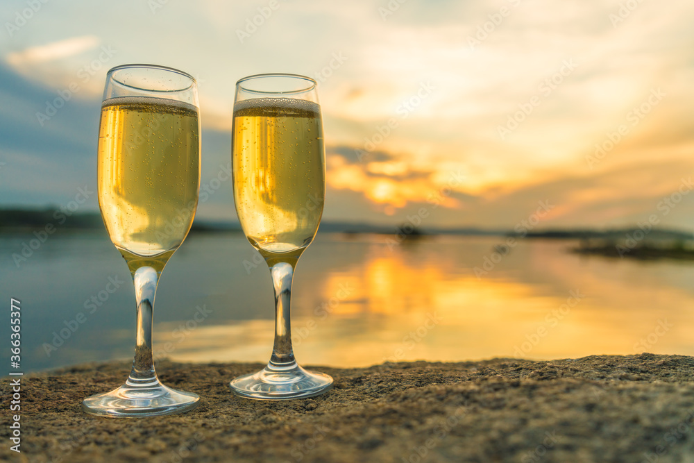 Two glasses with champagne on the background of the sunset, in nature, outdoors. Ramontic evening for lovers