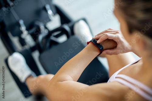 Close-up of sportswoman using fitness tracker while working out in a gym.