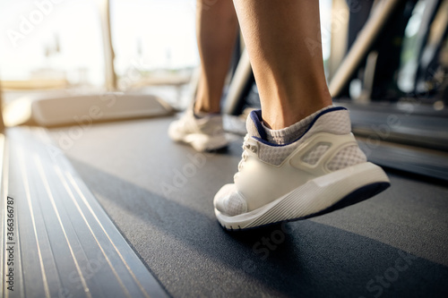 Close-up of athletic woman exercising on treadmill in a gym.