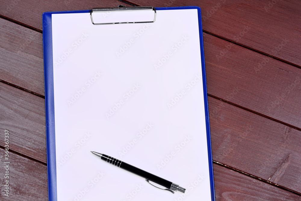 Empty clipboard with pen on a wood table Empty clipboard with pen on a wood table