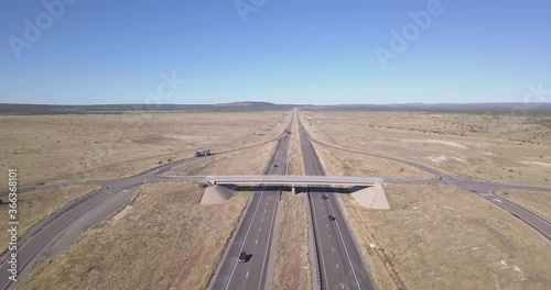 Aerial of Big Highway to Horizon in Dry grass plains showing Trucks and cars going by in United States of America