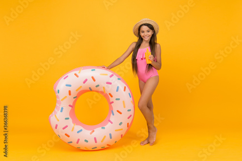 Enjoying suntan and vacation. cheerful small girl in swimsuit and straw hat. pool beach fun. child with tanning product. small beauty. happy kid and rubber ring. summer vacation activity. tanning oil