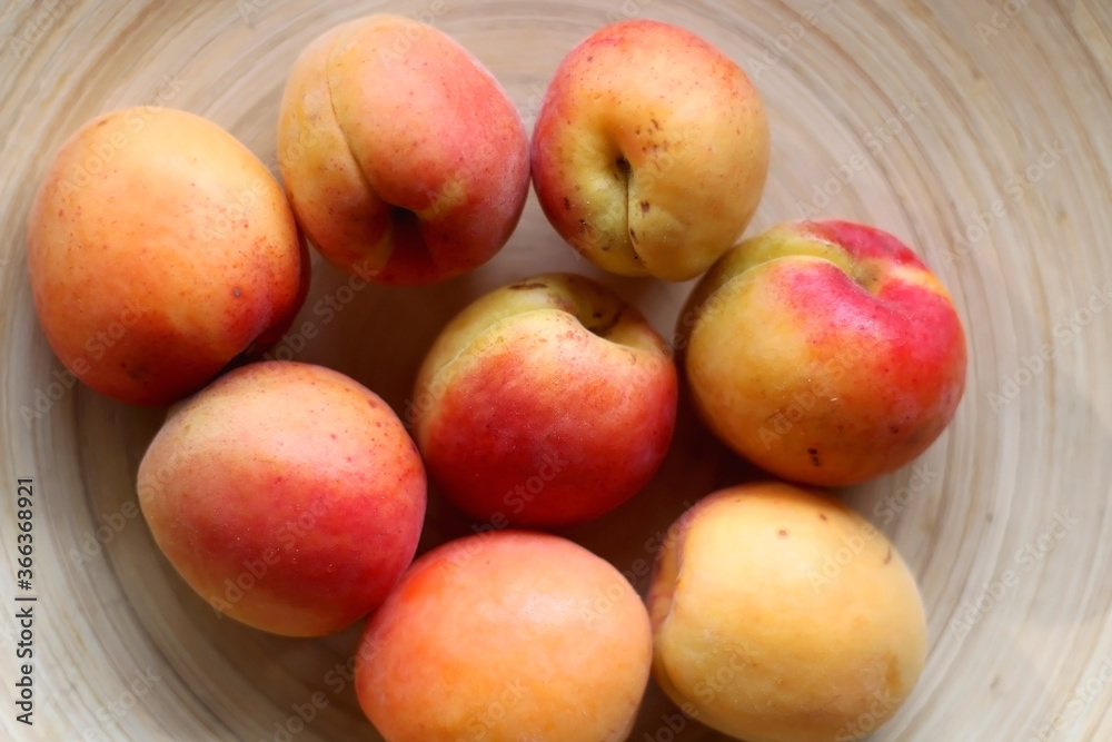 Wooden bowl with fresh organic apricots on the table. Top view. Wooden bowl with fresh organic apricots on the table. Top view.