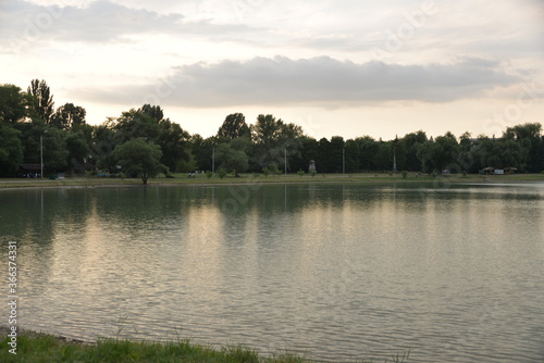 beautiful lake at sunset, the rays of the sun paint the water and small waves in gold, red, orange