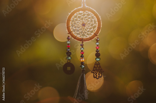 Close up of spiritual necklace with sacred geometry circle with bokeh background backlit by sunset golden light