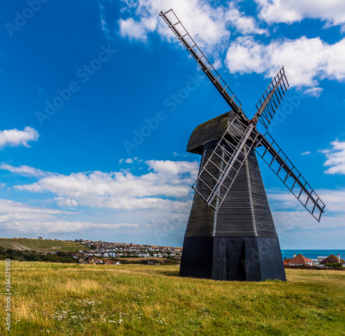 A view across Beacon Hill towards a smock windmill and the town of Rottingdean, Sussex, UK in summer