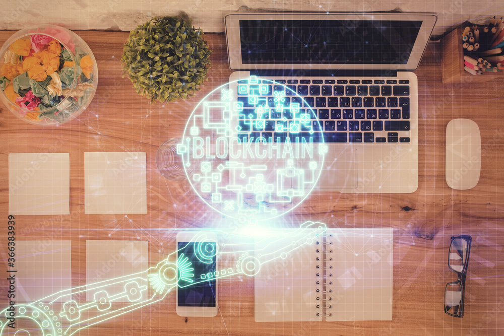 Blockchain theme hologram drawings over computer on the desktop background. Top view. Double exposure. Blockchain theme hologram drawings over computer on the desktop background. Top view. Double exposure.
