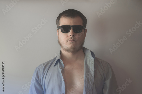 Man in blue shirt and dark sunglasses close up view.