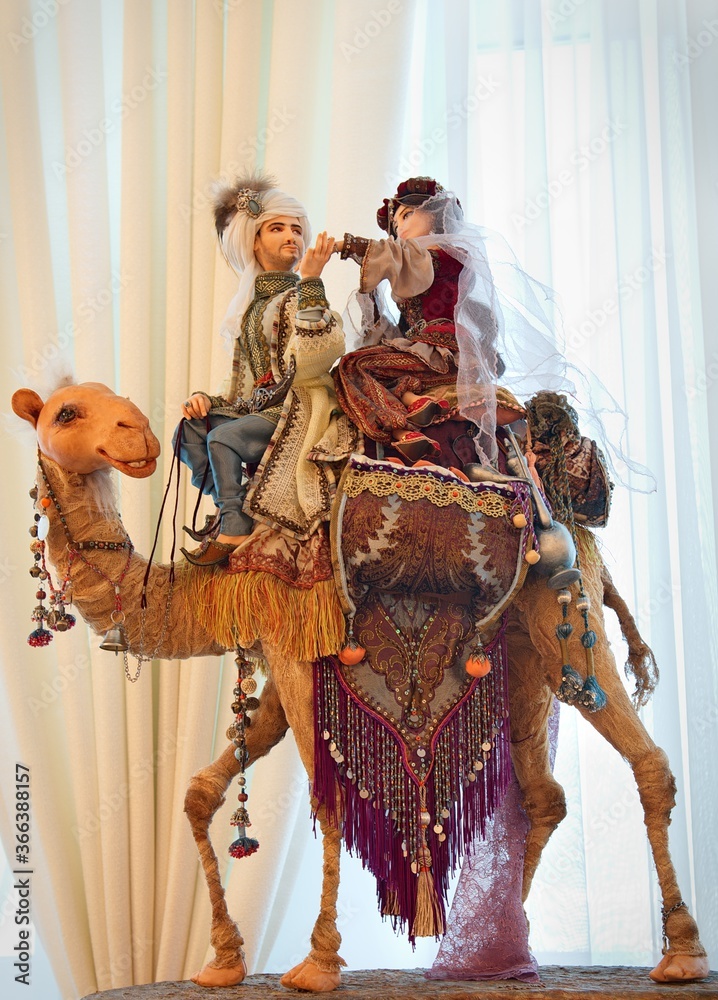 A doll of a guy and a girl from an oriental fairy tale on a camel. Fictional characters from a fairy tale. A doll of two lovers.