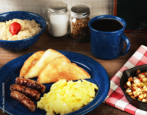 Foto A country style scrambled egg breakfast on a rustic wooden restaurant table with oatmeal, potatoes and coffee with warm side light