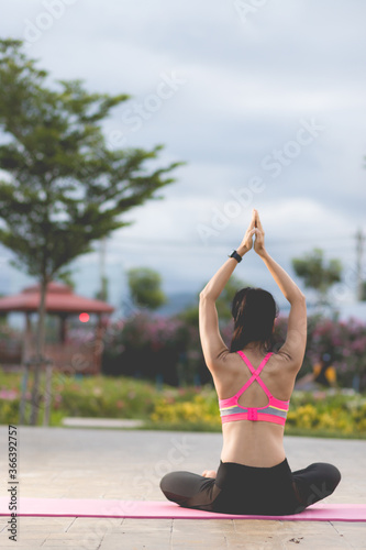 back view. Young women do yoga outdoors on stone. women exercising yoga in the park. Young girl meditating in lotus posture closeup.