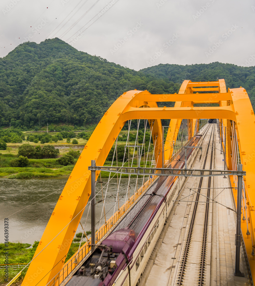 Top view of train crossing yellow bridge