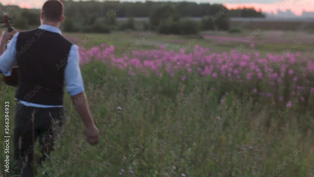 young man violinist is on the field at sunset inspired by nature flowers young man violinist is on the field at sunset inspired by nature flowers