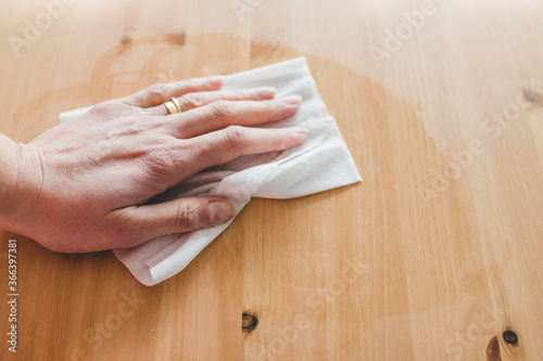 hand cleaning woooden coffee table with disinfectant wet wipe concept of the new normal after covid-19