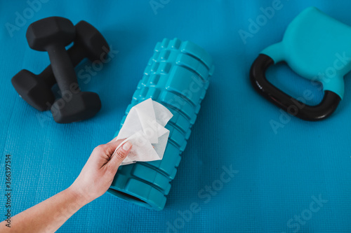 the new normal after covid-19, hand cleaning gym equipment with disinfectant wipe against virus and bacteria