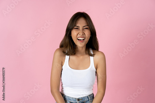 Cheerful young woman looking at camera against a plain pink background