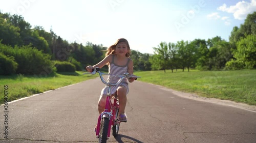front view, cute little girl Riding Bike On Driveway, At road, childhood concept, photo