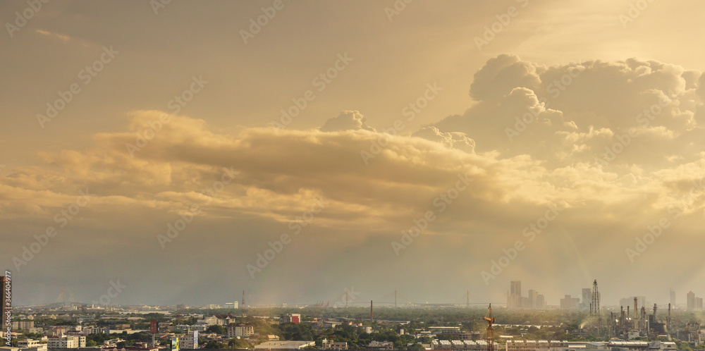 View of expanding city, changing environment. In the evening, the sun shines through cloudy sky and rain from the tower