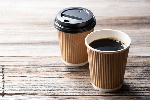 A paper cup of coffee on an old wooden background photo