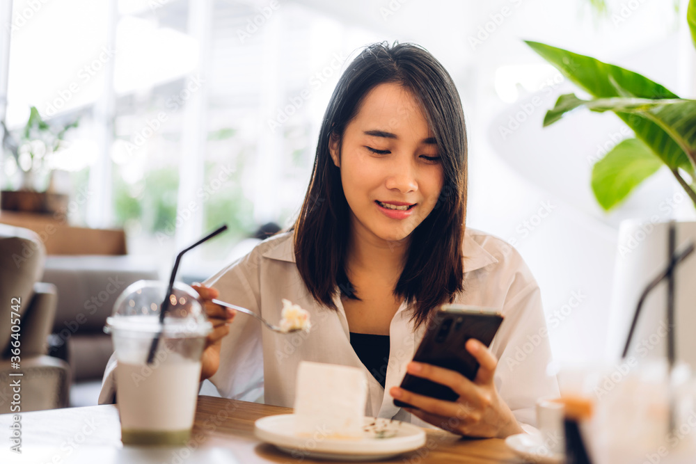 Portrait of smiling happy beautiful asian woman relaxing using digital smartphone.Young asian girl looking at screen typing message and playing game online or social media at cafe Portrait of smiling happy beautiful asian woman relaxing using digital smartphone.Young asian girl looking at screen typing message and playing game online or social media at cafe