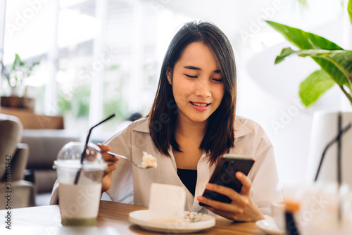 Portrait of smiling happy beautiful asian woman relaxing using digital smartphone.Young asian girl looking at screen typing message and playing game online or social media at cafe