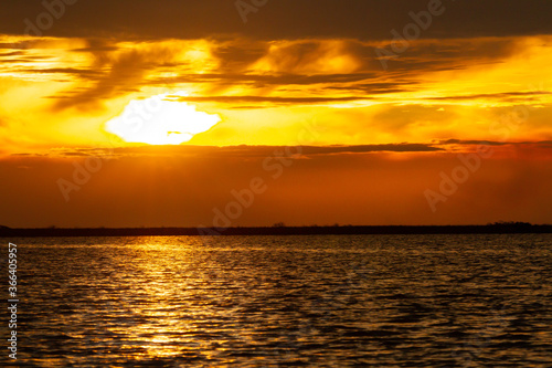 Beautiful sunset with the sun on the horizon reflecting the golden light in the lake water © HC FOTOSTUDIO