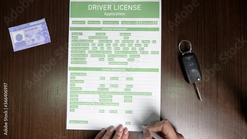 Woman filling in driver license application at table, top view
