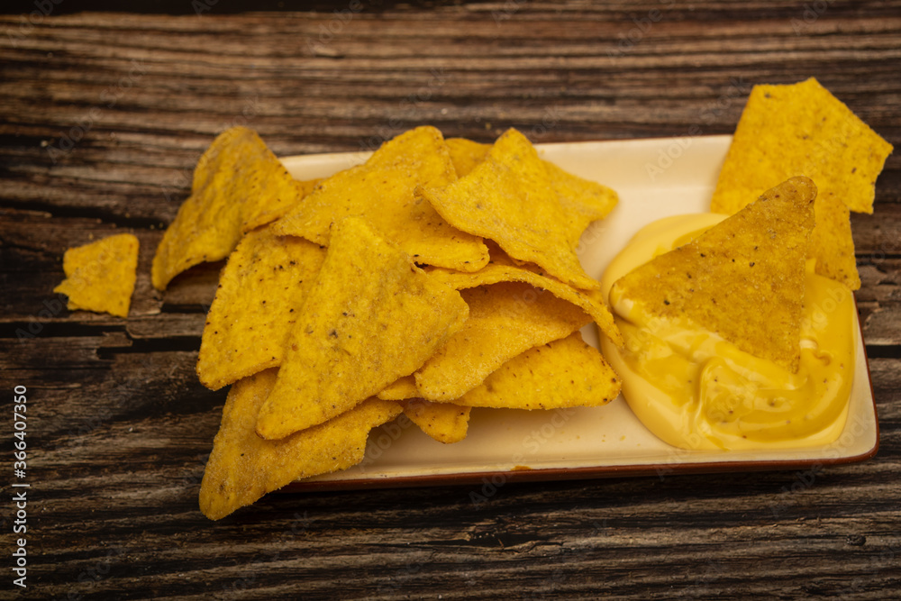 Corn chips with cheese sauce on a wooden background. Close up. Corn chips with cheese sauce on a wooden background. Close up.