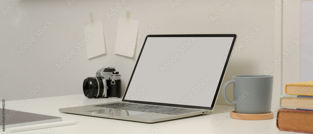 Study table with mock up laptop, books, coffee cup, camera and digital tablet on white table Study table with mock up laptop, books, coffee cup, camera and digital tablet on white table