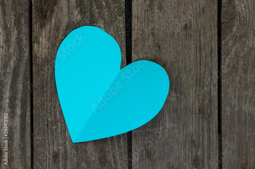 one paper blue heart cut out lies on a wooden background close-up photo