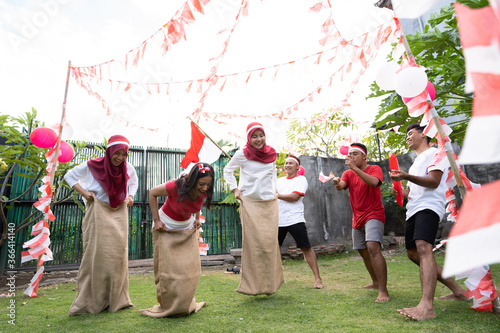 male supporters wearing the red and white attribute shouted in support of the women's sack racer event commemorating Indonesia's Independence Day celebrations on the lawn
