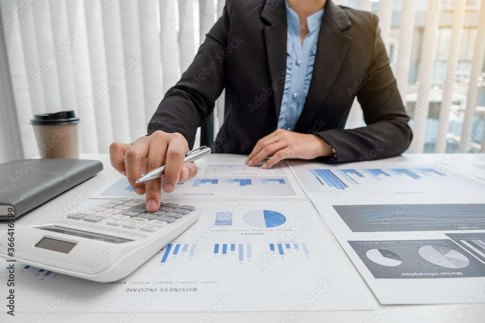 The hands of a male businesswoman use the calculator are analyzing and calculating the annual income and expenses in a financial graph that shows results To summarize balances overall in office The hands of a male businesswoman use the calculator are analyzing and calculating the annual income and expenses in a financial graph that shows results To summarize balances overall in office