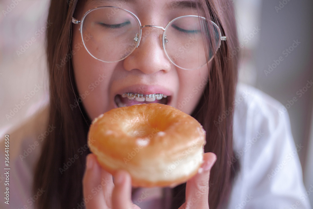 Photo of sugar addicted woman smells freshly baked donuts, impossible to resist eating dessert, ready to eat dessert with good appetite, enjoys homemade bakery. Photo of sugar addicted woman smells freshly baked donuts, impossible to resist eating dessert, ready to eat dessert with good appetite, enjoys homemade bakery.