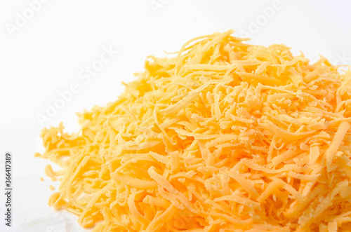 Grated hard cheese on a white plate. Russian cheese, Dutch, parmesan heap grated on a white plate in a close-up top and top view