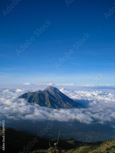 The landscape of Mount Merapi in Central Java, Indonesia, with a background of blue sky, edelweiss trees and clouds