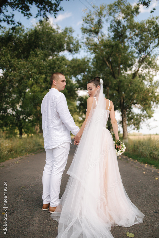 Back view of groom and bride walking in linden aley in wedding day Back view of groom and bride walking in linden aley in wedding day