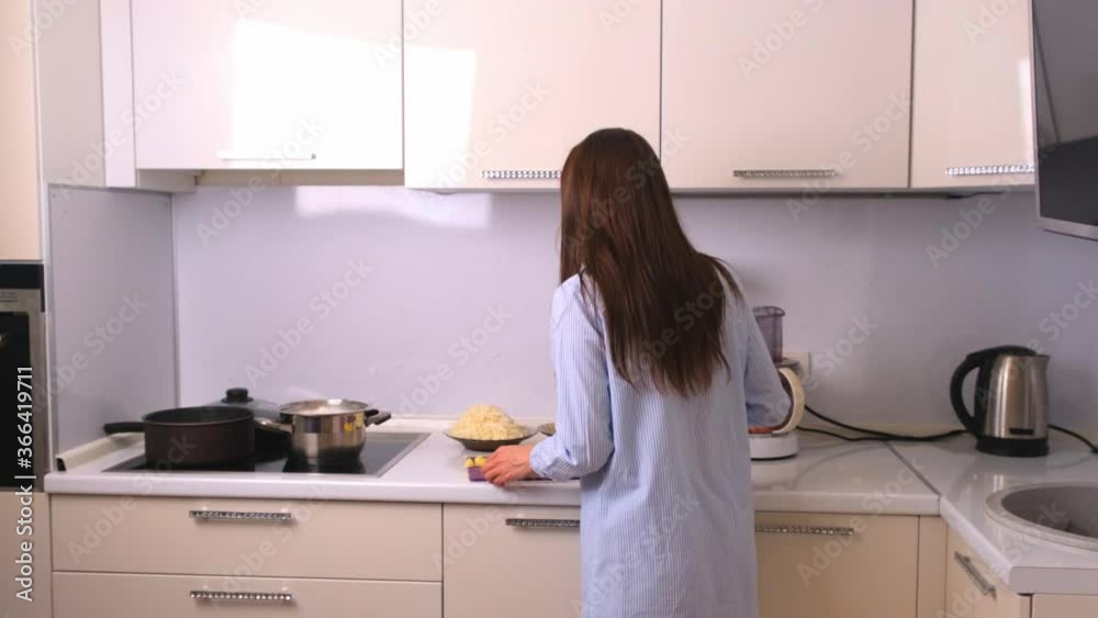 Young and beautiful housewife woman cooking in a white kitchen. Young and beautiful housewife woman cooking in a white kitchen.