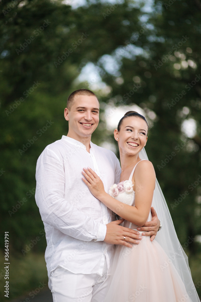Young and beautiful bride with handsome groom hug each other kiss and smile. Portrait of happy wedding couple Young and beautiful bride with handsome groom hug each other kiss and smile. Portrait of happy wedding couple