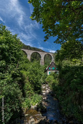 Spectacular view of an old house in front of the old railway bridge at the Ravenna gorge viaduct in Breitnau, Germany