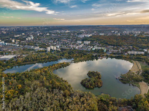 Aerial view of a lake in a park with autumn trees. Kishinev, Moldova. Epic aerial flight over water. Colorful autumn trees in the daytime. © Igor Syrbu